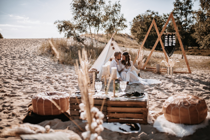 Ein Brautpaar, welches in einem gemütlichen Zelt im Sand sitzt