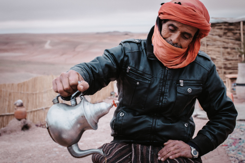 Ein Mann mit einem Turban schenkt Tee in der Wüste ein